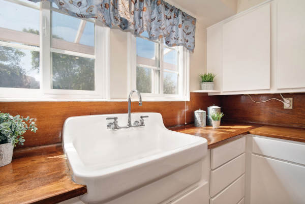 A charming farmhouse kitchen sink with natural wood countertops and a bright window view.