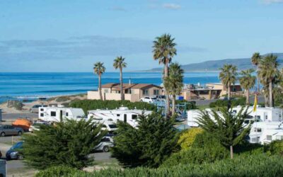oceanfront-rv-park-coastal-campground-scenic-view Oceanfront RV park and coastal campground with palm trees, parked trailers, and views of the blue ocean and hills.