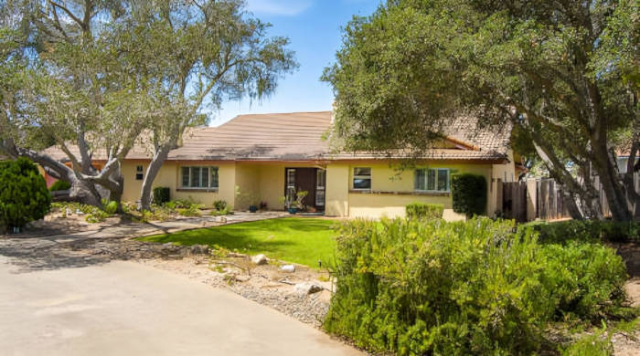 A charming family home with a well-maintained lawn and beautiful trees.